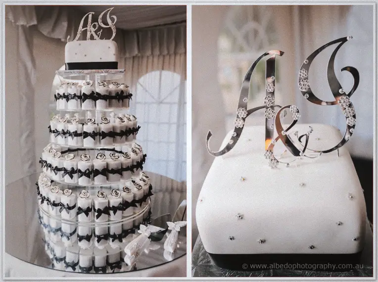 Tall cake tower of black-ribboned rolls beside a mirrored monogram on the white top tier.