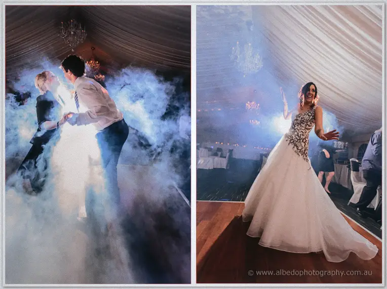 Guests dance waist-deep in fog while Jenna strikes a joyful pose on the glowing floor beyond.