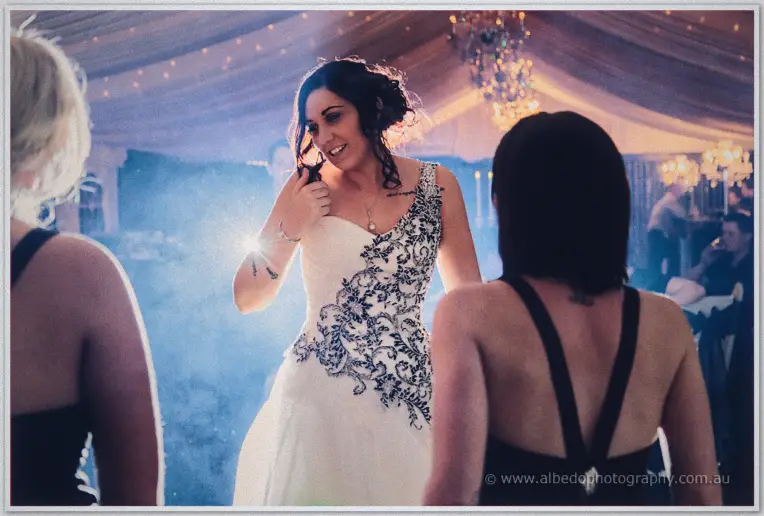 Jenna dances surrounded by friends in black dresses, flanked by warm candlelight and drifting haze.