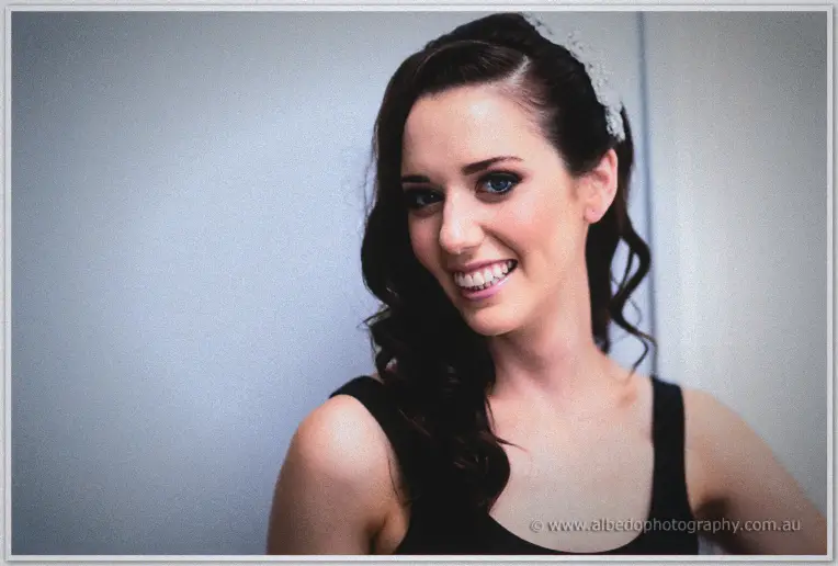 Karis smiles brightly in her lace headpiece and smoky bridal makeup