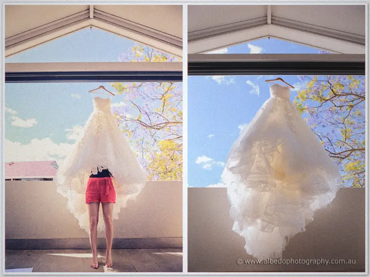Karis's strapless gown hangs from a balcony beam against blue sky and blossom