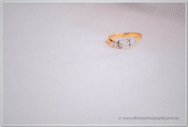 Gold trilogy diamond ring glimmers on soft white tulle in gentle light