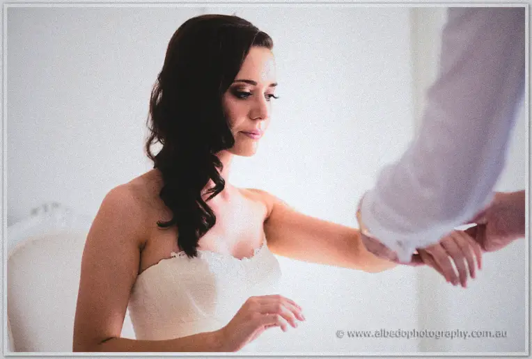A bracelet is slipped onto Karis's wrist as she waits in her lace wedding gown