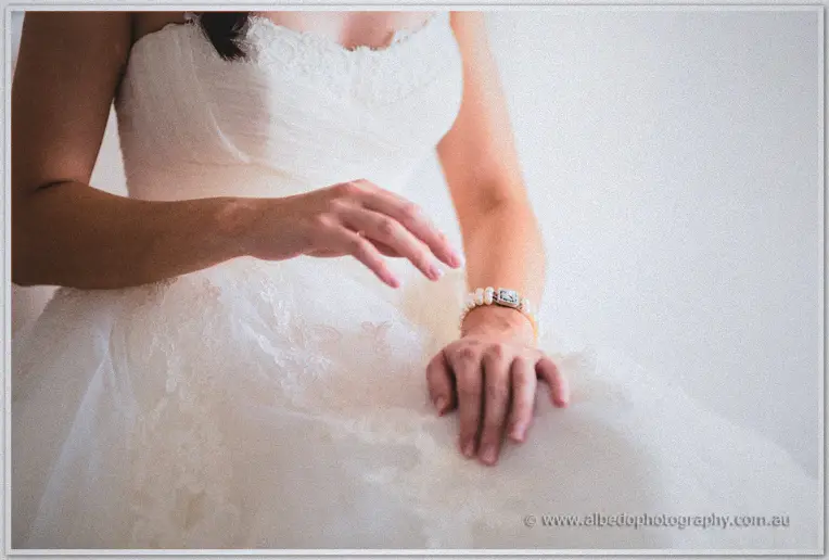 Detail of the bride's hands resting on her tulle skirt with pearls and a ring