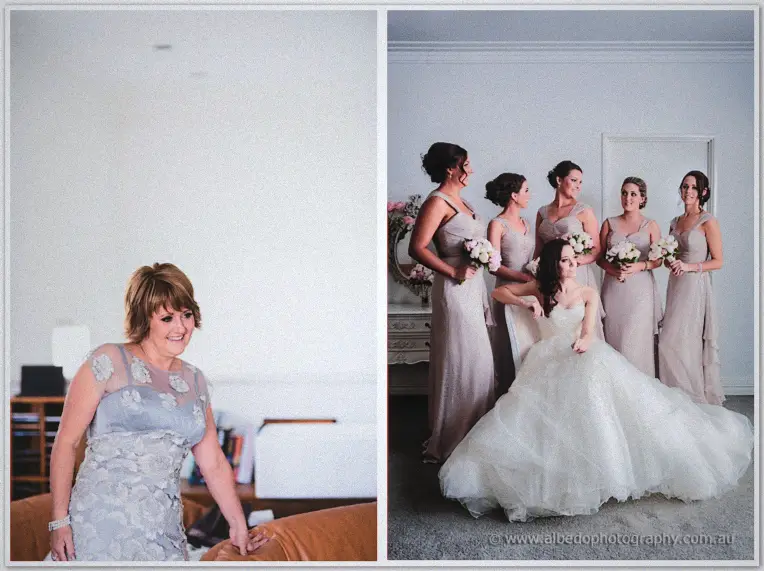 Mother of the bride in a grey floral dress smiles from the couch beside a bridesmaid group portrait