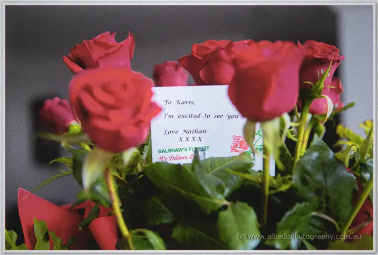 Red roses surround a handwritten card from Nathan tucked among the blooms