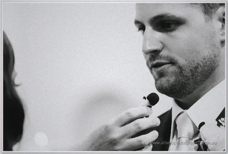 Close monochrome profile of Nathan speaking his vows into a small microphone