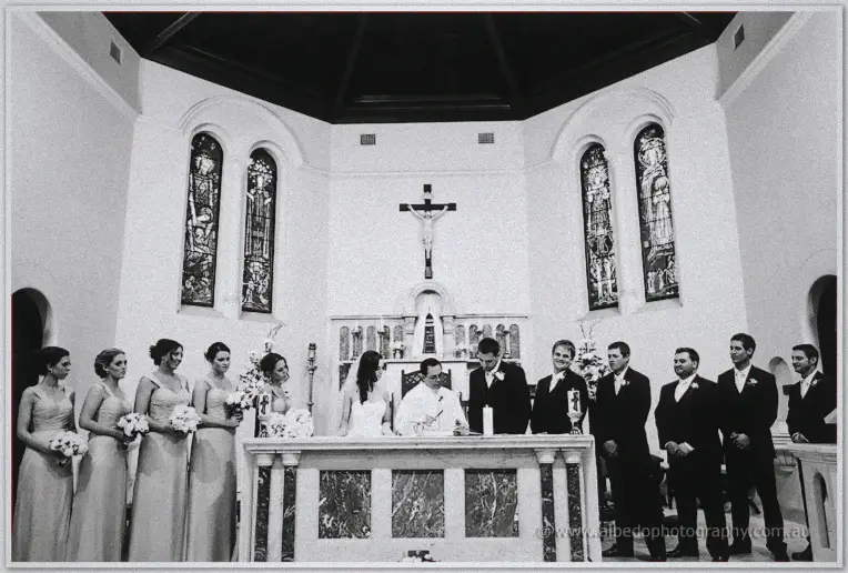The couple signs the register at the marble altar flanked by their wedding party