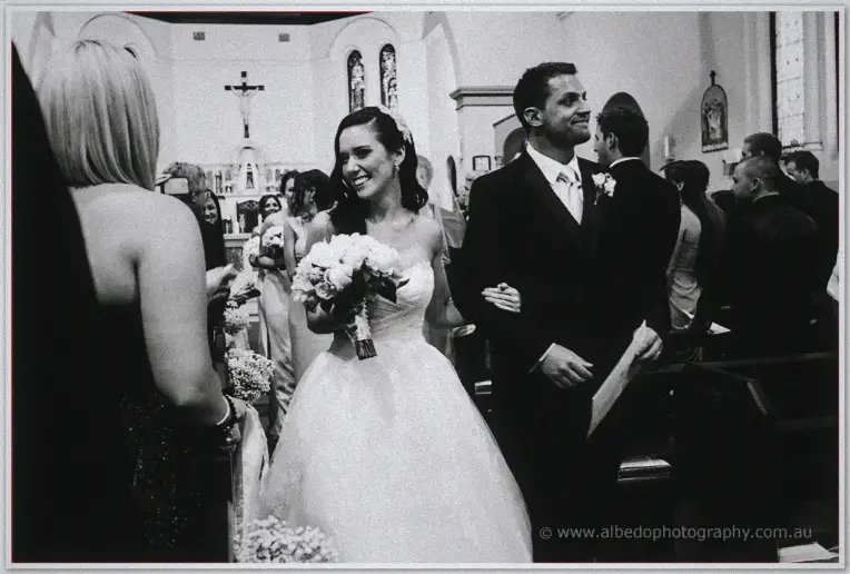 Karis grins walking back up the aisle arm in arm with Nathan past smiling guests