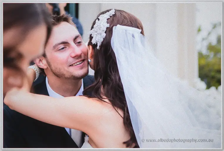 Karis embraces a beaming guest outside, her crystal comb and veil catching soft light