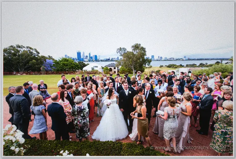 Karis and Nathan greet a crowd of guests on a terrace above the Swan River skyline