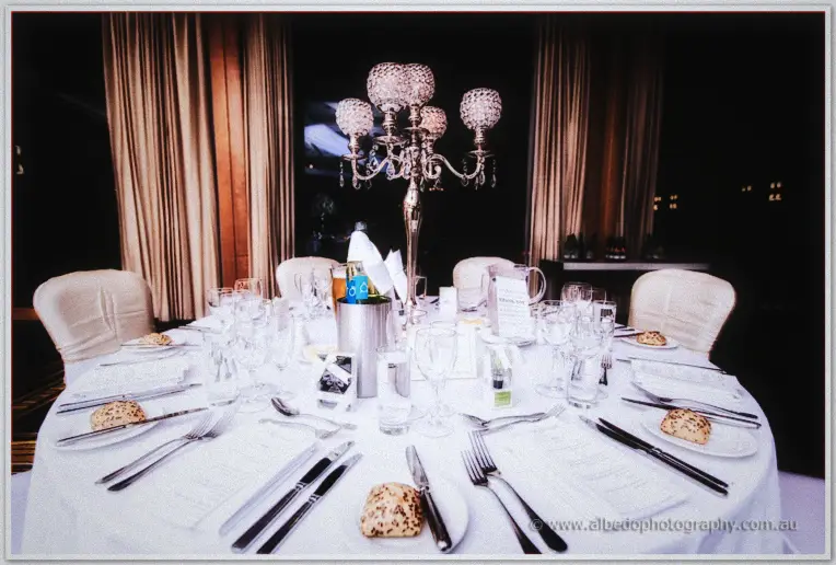 A crystal candelabra centrepiece crowns the reception table set with white linen and polished glassware