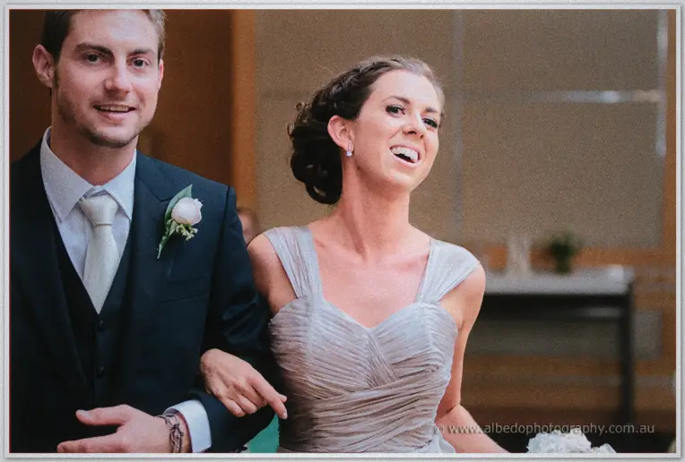 Another groomsman and bridesmaid walk the aisle arm in arm, both grinning broadly