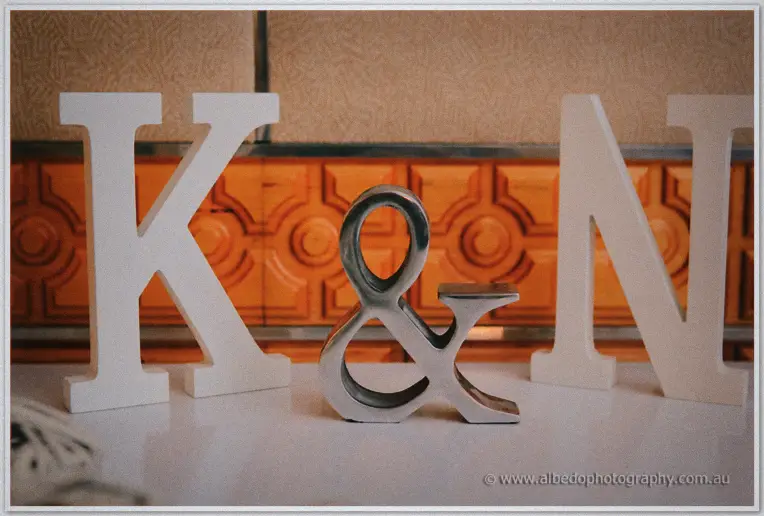 White K and N letters flank a silver ampersand on the bridal table against orange panelling