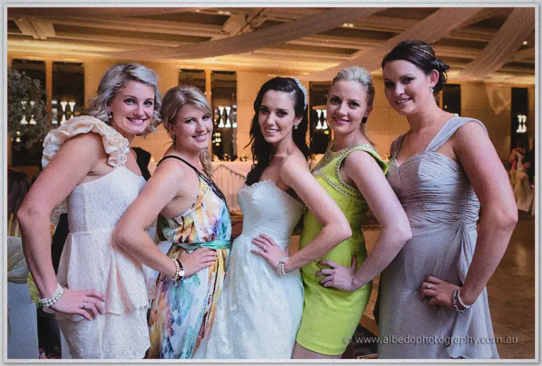 Karis poses hands on hips with four friends in bright cocktail dresses on the dance floor