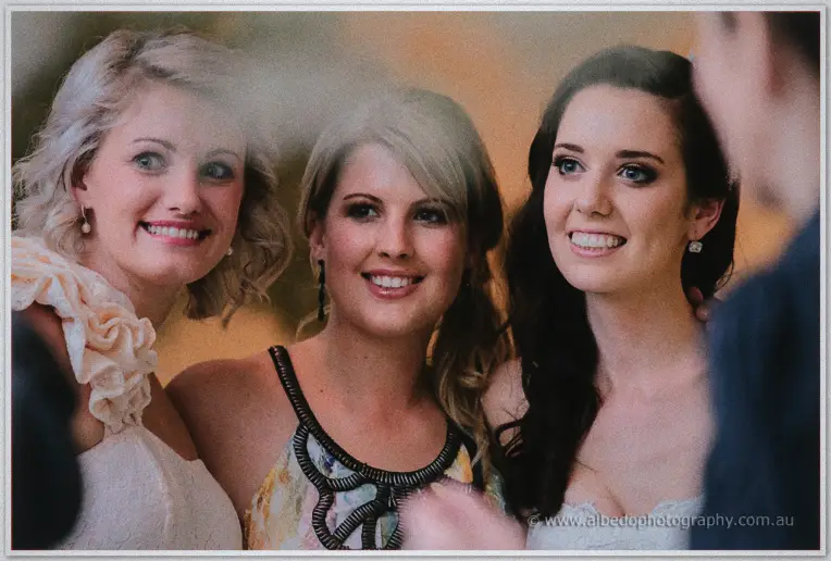 Three grinning friends lean in around Karis in a warm candid on the dance floor