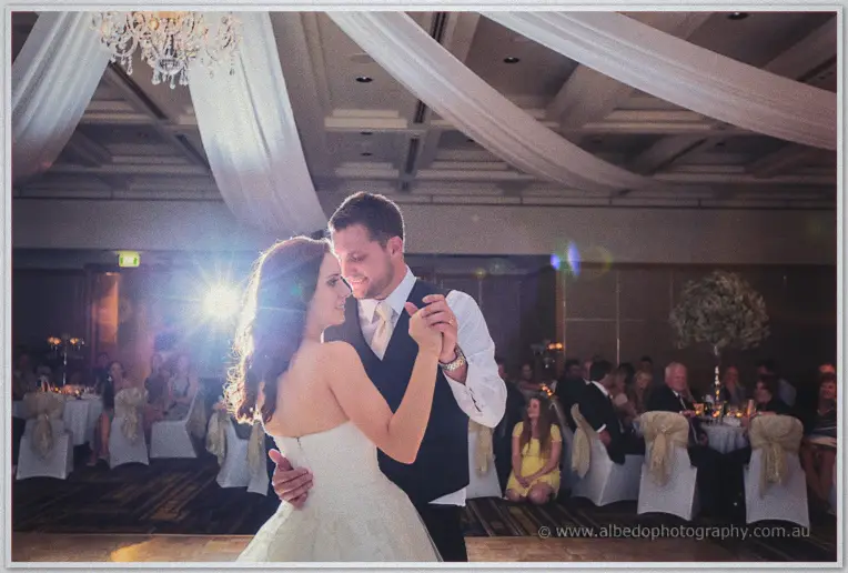 Karis and Nathan sway cheek to cheek as guests watch from candlelit tables