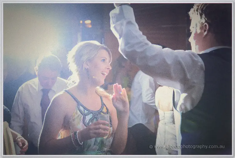 A guest sings along drink in hand as the packed dance floor lights up behind her