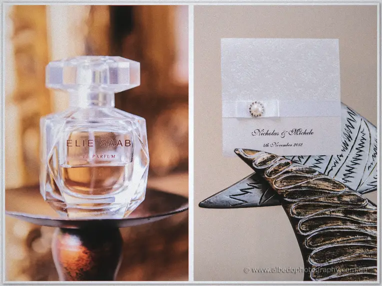 Faceted glass perfume bottle beside a pearl-brooch invitation for Nicholas and Michele in golden light