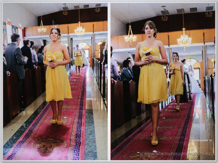 Two bridesmaids in yellow walking the red-carpeted aisle of the candlelit Orthodox church