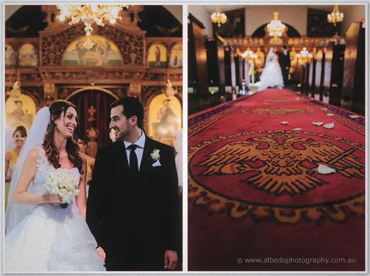 Michele and Nick smile by the iconostasis with the petal-strewn aisle of the Orthodox church behind.