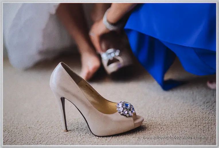 Champagne peep-toe heel with crystal brooch on the carpet as Allison slips on the other shoe