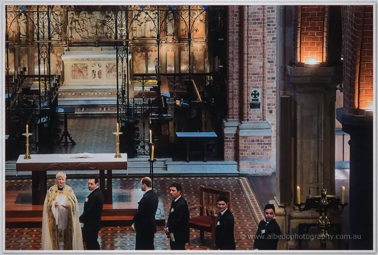 Groomsmen waiting at the candlelit altar with the priest before the ceremony at St George's Cathedral