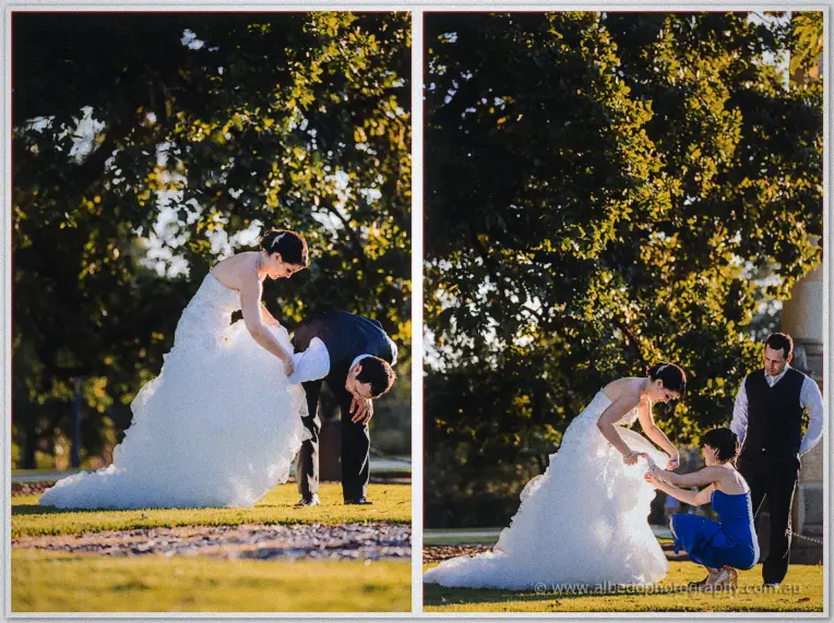 Allison laughs as Greg shakes grit from her gown on the lawn while a bridesmaid kneels at the hem.
