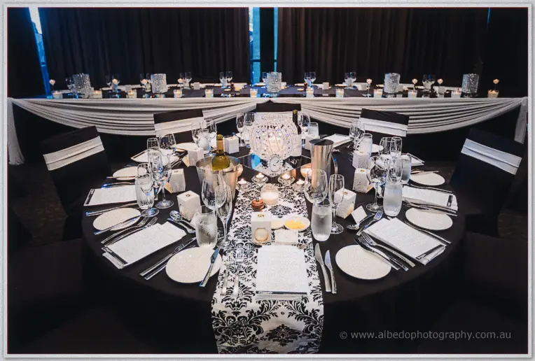 A round table dressed in black and white damask runner, crystal candelabra glowing at the room's dim centre.