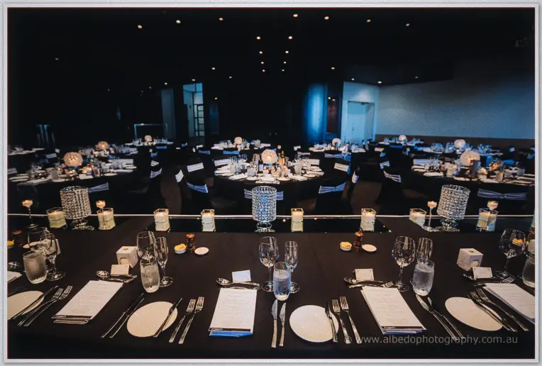 Candlelit reception tables at Frasers set with black linen, crystal tealight holders and mirror centrepieces.