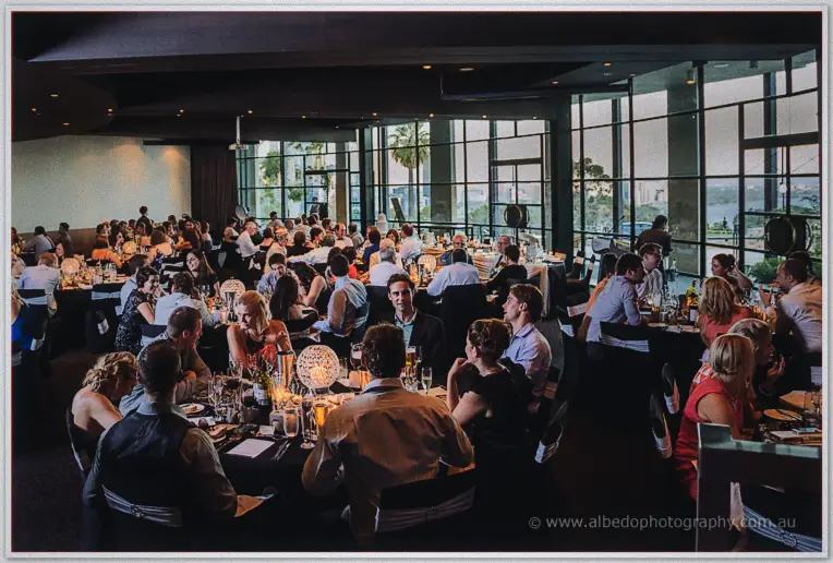 Guests packed around candlelit tables as evening light fades through Frasers' floor-to-ceiling windows.