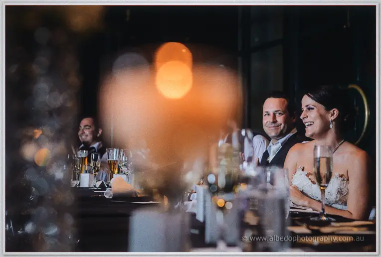 Allison laughs during speeches as candlelight blurs warm across the bridal table at Frasers.