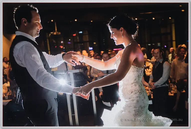 First dance at Frasers, guests crowding the floor as Allison spins with Greg in flare-lit haze.