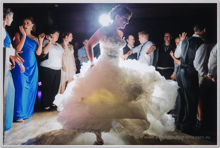 Allison twirls solo in her voluminous tulle gown, guests cheering in a ring around the flare-lit floor.
