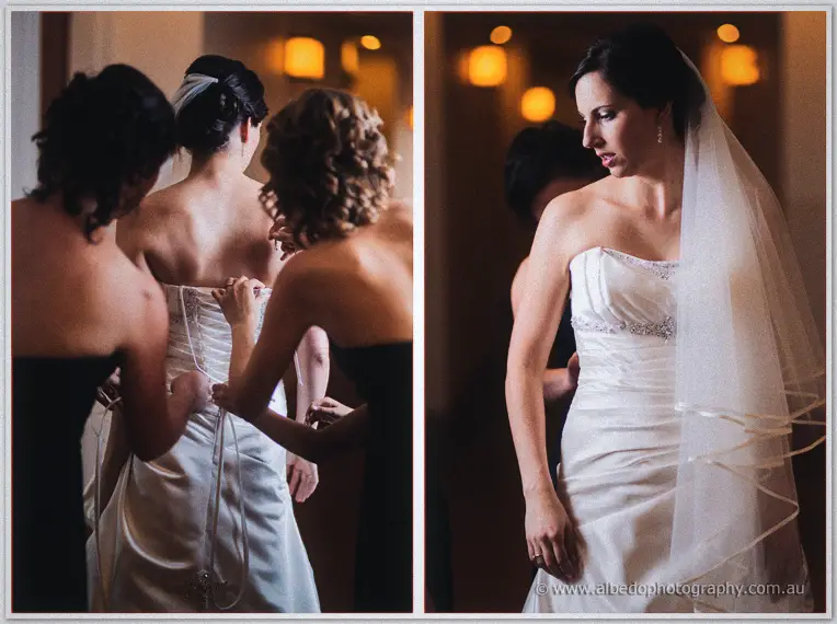 Bridesmaids lace the back of Felicity's ivory gown, then she waits in her veil in golden corridor light