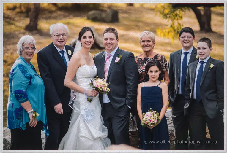 Felicity and Mark pose with family in the golden parkland at Inglewood Estate, flower girl holding her posy.