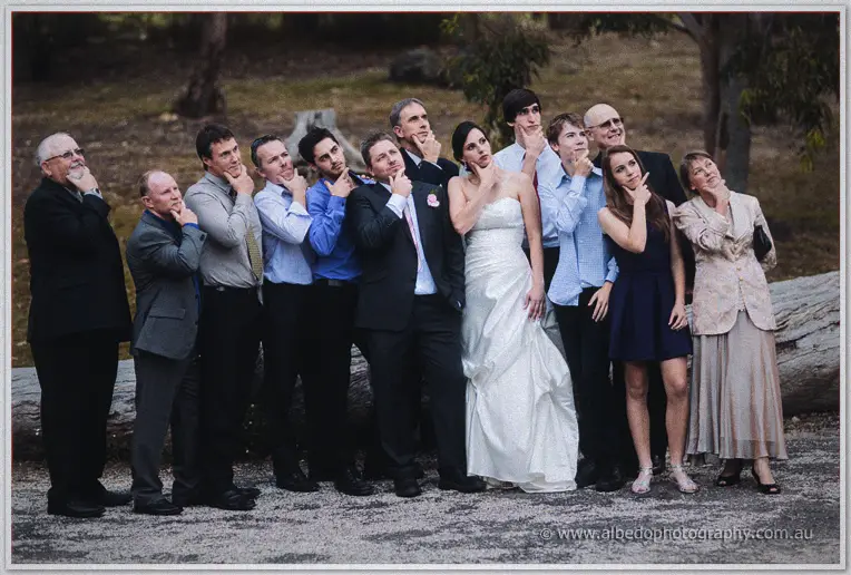 Felicity and the wedding party strike deadpan thinking poses beneath a fallen log at Inglewood Estate.