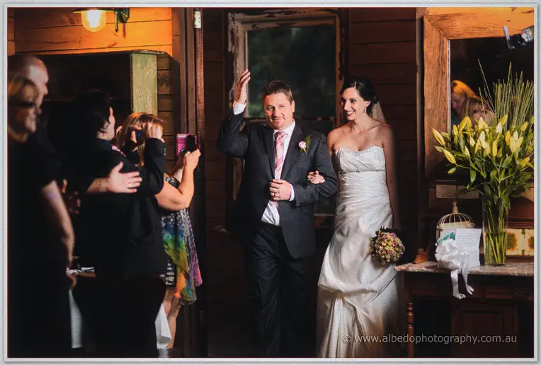 Mark waves as the pair enter the warmly lit homestead to cheering guests.