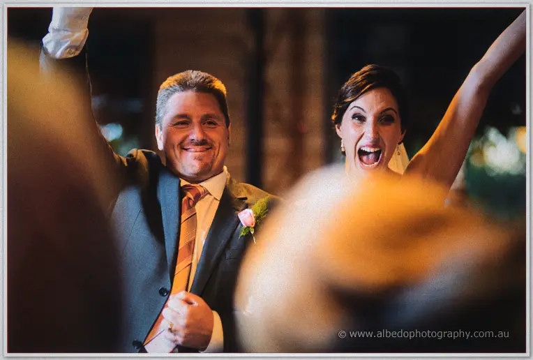 The couple throw their arms up cheering as they make their reception entrance.