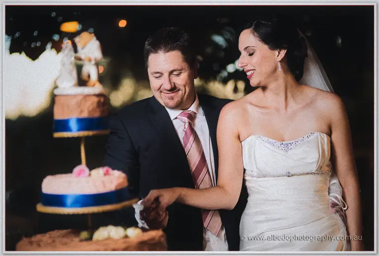 Felicity steadies the knife as the pair cut their tiered cake at night.