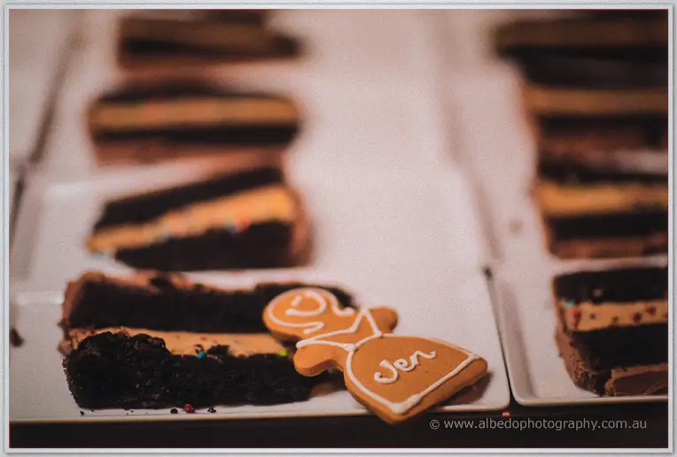 A bride-shaped gingerbread cookie rests among slices of chocolate cake.