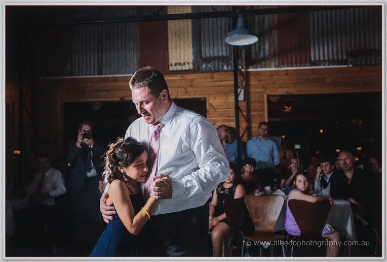 Mark shares a slow dance with the young flower girl as guests watch on.