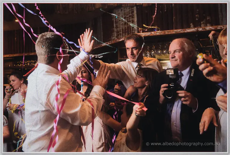Mark high-fives guests through a flurry of pink streamers on the dance floor.