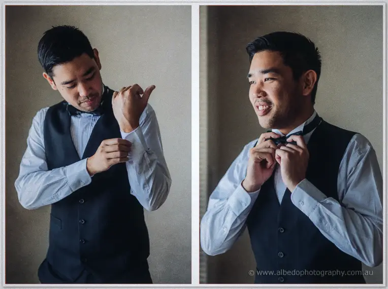 Groom Chris fastens a cufflink and adjusts his black bow tie in soft window light during preparations.