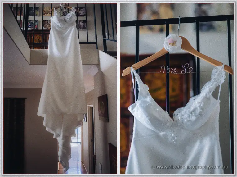 Kristyn's lace-detailed gown hangs from a stairwell railing beside a wire 'Mrs Le' hanger.