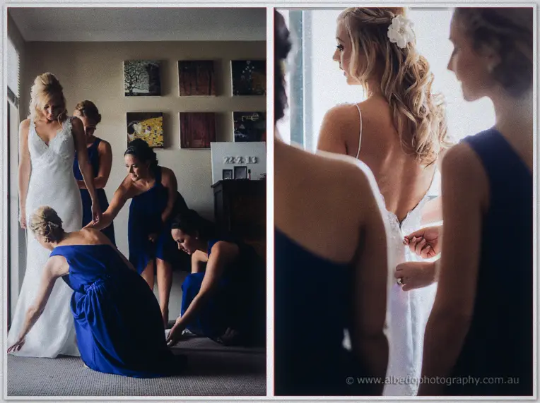 Bridesmaids in royal blue kneel to arrange Kristyn's train and fasten the back of her gown.