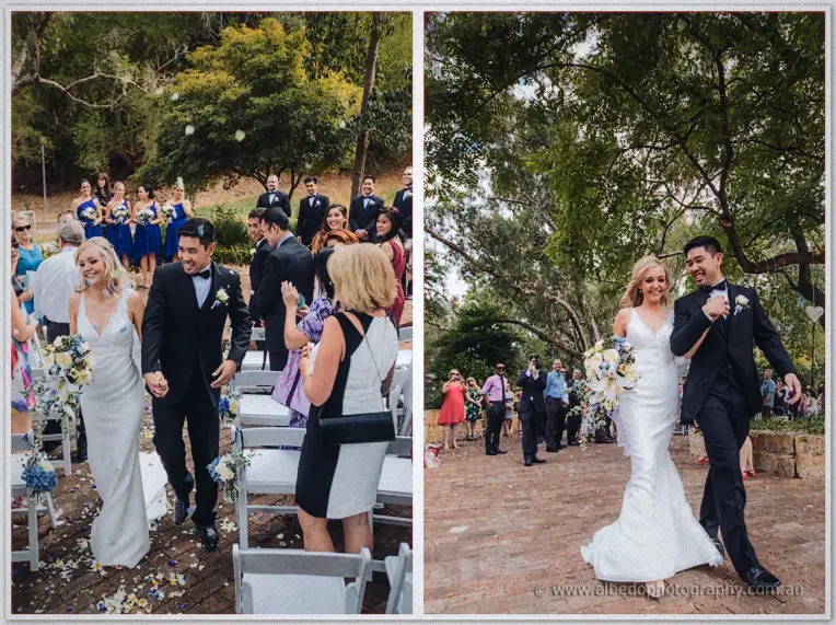 The newlyweds walk back down the aisle hand in hand through petals and confetti as guests applaud.