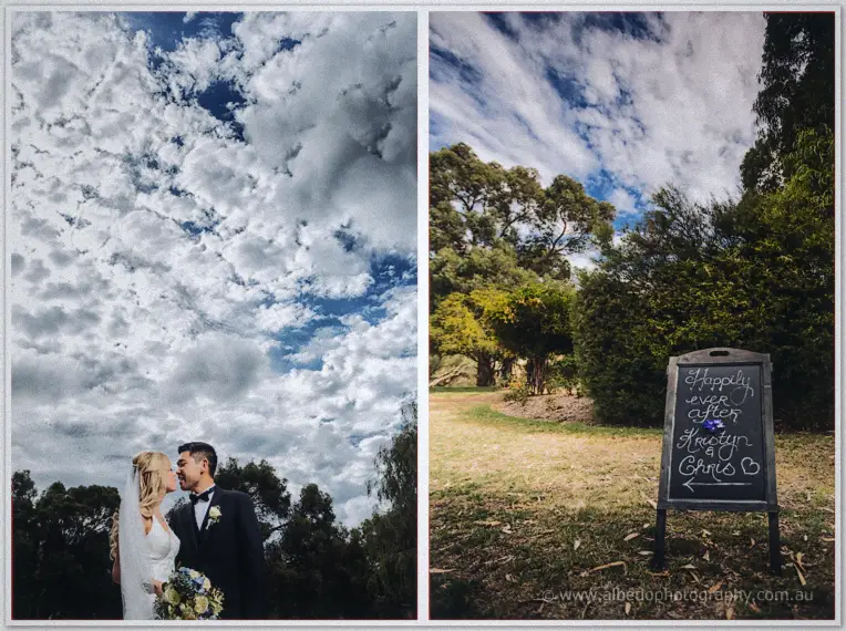 Kristyn and Chris kiss beneath towering clouds, beside a chalkboard reading happily ever after.