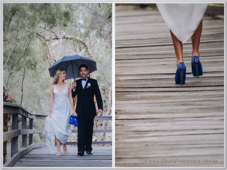 Sheltered under one umbrella, the couple stroll the boardwalk while Kristyn carries her sparkly blue heels