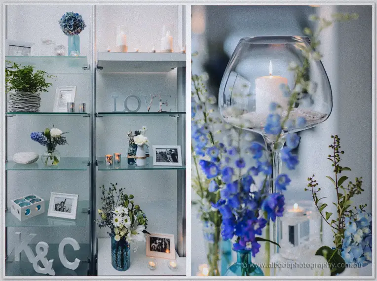 Styled shelves of white and blue blooms, candles and K and C letters sit beside a goblet candle centerpiece